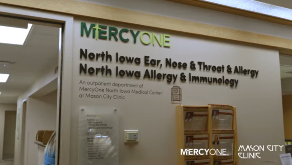 Clinic entrance with sign for North Iowa Ear, Nose & Throat & Allergy, and North Iowa Allergy & Immunology. It mentions an outpatient department of MercyOne North Iowa Medical Center at Mason City Clinic. Logos for MercyOne and Mason City Clinic are visible.